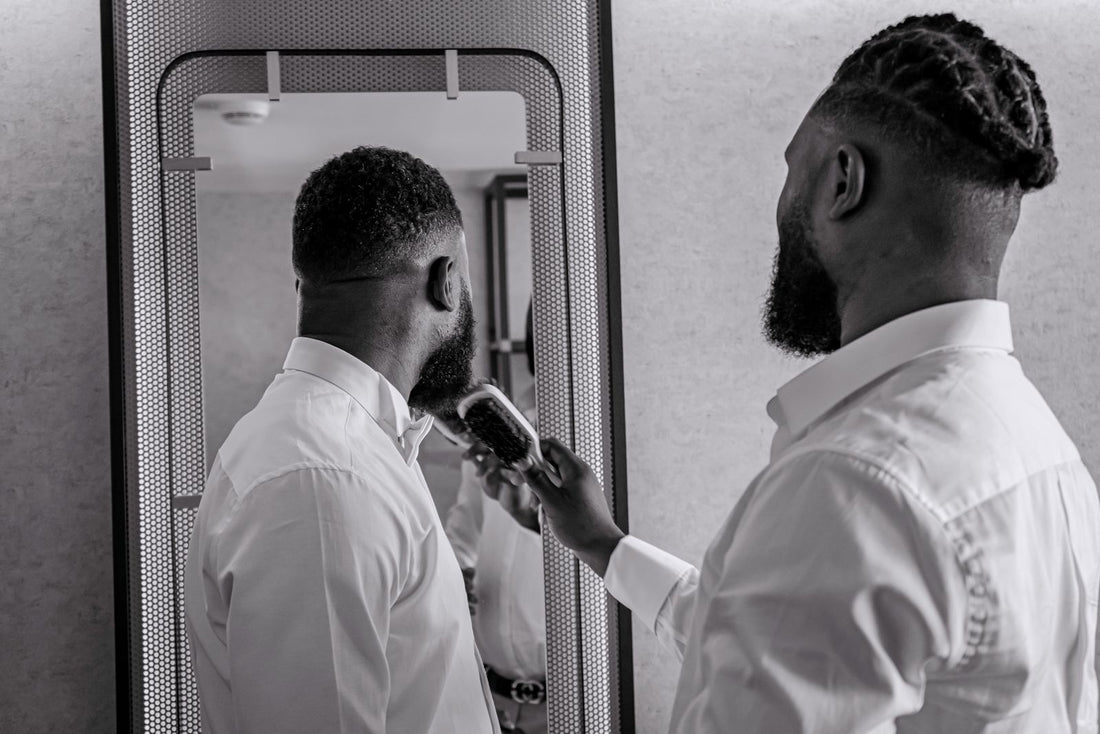 Homme en chemise blanche qui brosse sa barbe devant le miroir, rituel du matin