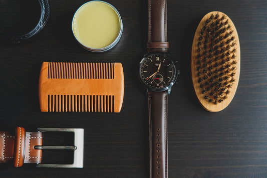 Peigne à barbe en bois et brosse à barbe côte à côte avec une montre et un baume